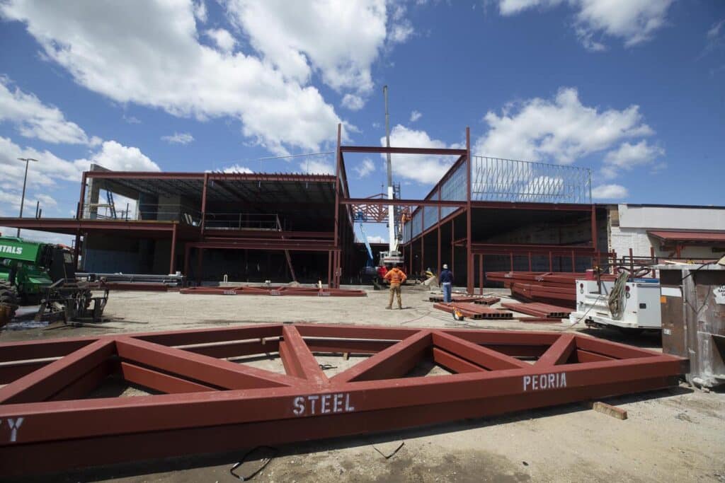 design-build construction scene; workers place steel frames