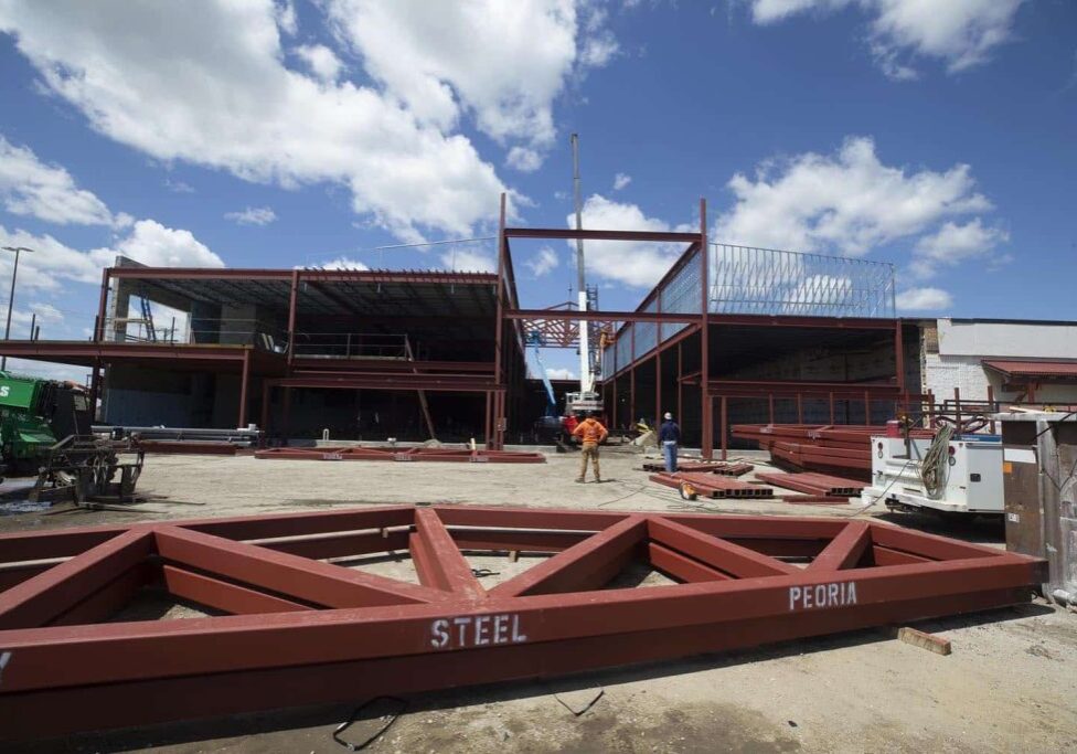 design-build construction scene; workers place steel frames