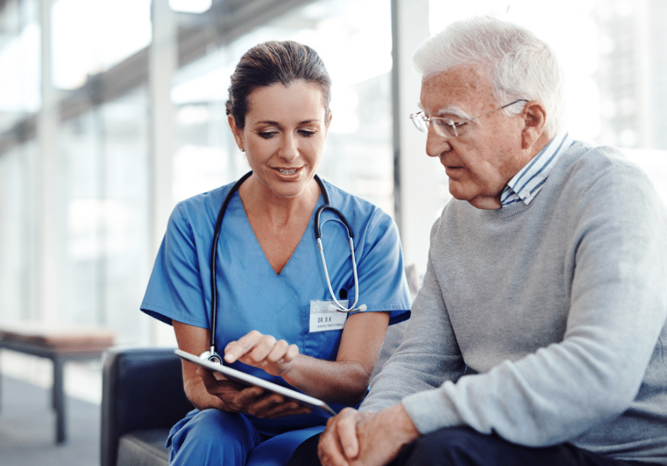 Health care worker shows senior man how to use an iPad for healthcare management.