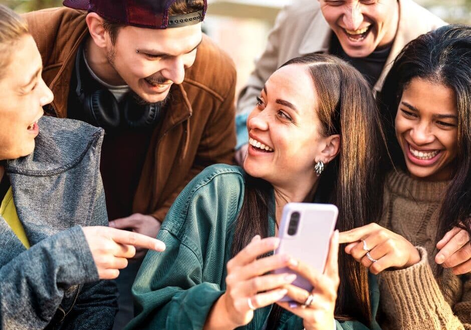 A group of Gen Z adults interacting with each other and their smart phones