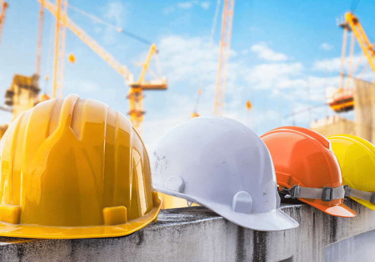 Hard hats with construction cranes in background illustrate current procurement and labor pool situation.